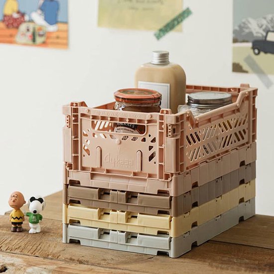 Stapel van pastelkleurige AyKasa vouwkratten, gevuld met potjes en een flesje.