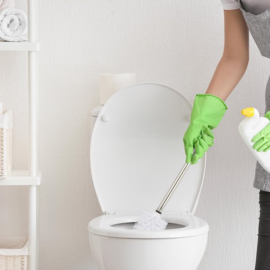Een persoon met groene handschoenen maakt een toilet schoon met een witte toiletborstel.