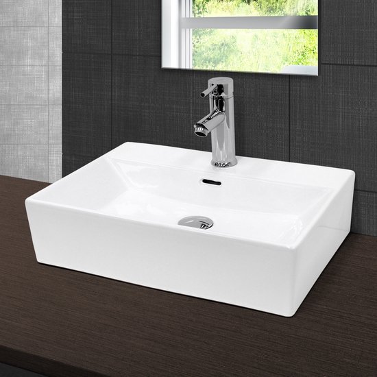 Lavabo rectangulaire en céramique blanche avec robinet chromé et évacuation, sur un plan de travail en bois foncé avec des carreaux gris.