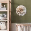 Wandcirkel met witte dahlia, beige midden, in een kinderkamer met houten meubels.