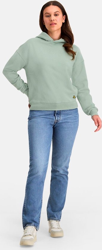 Model in een mintgroene NOMAD hoodie en jeans kijkt opzij.