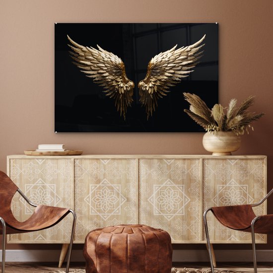 Gouden engelenvleugels op zwarte achtergrond boven een dressoir met stoelen.