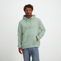 Man in mintgroene hoodie met logo, handen in de zak, op een witte achtergrond.