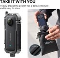 Een persoon plaatst de Insta360 X3 in een zwarte Ulanzi kooi in een PU-trekoordtasje. De tekst "TAKE IT WITH YOU" is zichtbaar.