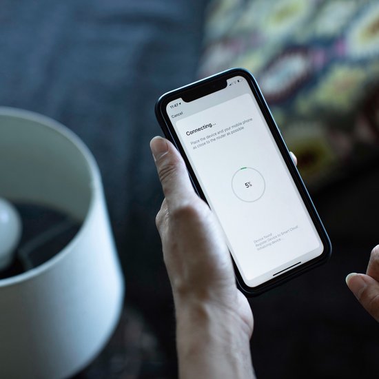 Een hand houdt een smartphone vast met het verbindingsscherm. De tekst zegt "Connecting..." met een voortgangsbalk van 5%.