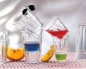 Verres empilés avec des boissons bleues et rouges, des tranches d'orange et un raisin.