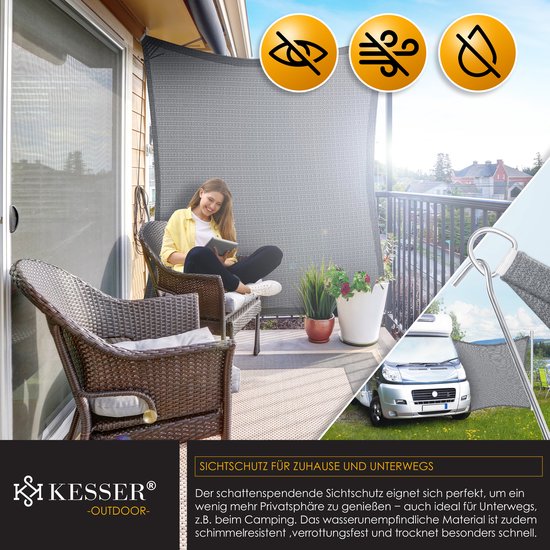 Een vrouw zit op een stoel op een balkon onder een grijs schaduwdoek, met een camper zichtbaar in de achtertuin.