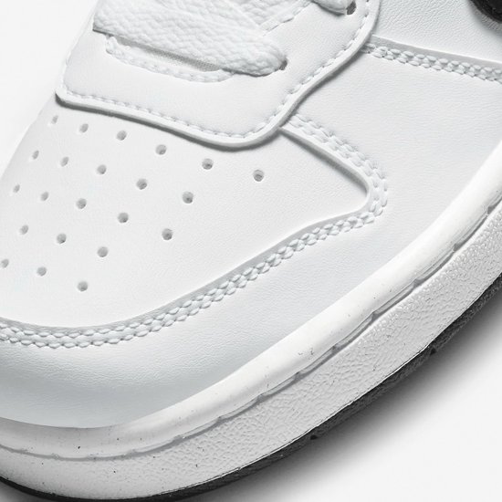 Detail van de neus van een witte Nike sneaker met perforaties en stiksels.