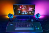 Gaming bureau met Razer speakers, toetsenbord, muis en monitor met oranje/paars licht.