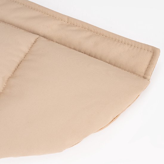 Detail van de gewatteerde naden van de beige hondenjas.