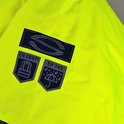 Close-up van certificeringslogo's op een felgele jas: EN 20471, EN 343 en een gestileerd logo.