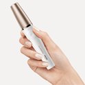 Hand houdt een witte Braun FaceSpa Pro epilator met rosegouden dop vast.