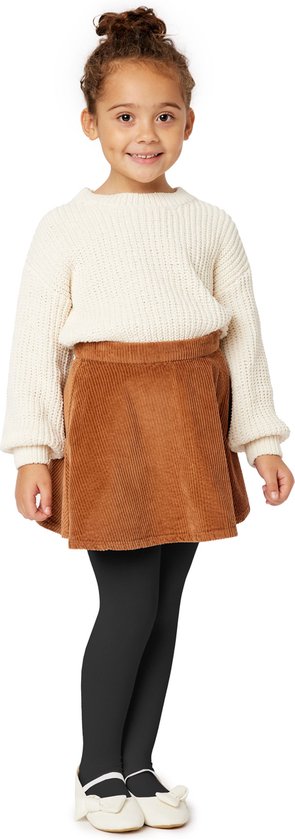 Meisje met bruine corduroy rok, crème gebreide trui en zwarte panty.