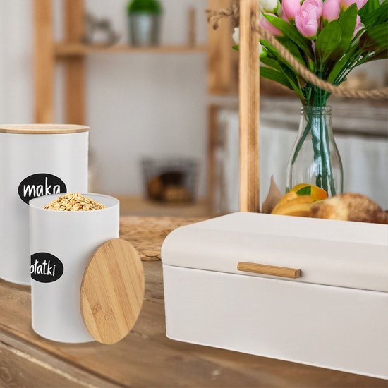 Boîte à pain métallique blanche avec poignée en bois, à côté de pots de conservation blancs, dans un décor de cuisine.