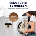 Femme plaçant un canapé pour chien de couleur crème dans une machine à laver. Texte "EENVOUDIG TE WASSEN". Détail d'une fermeture éclair visible.