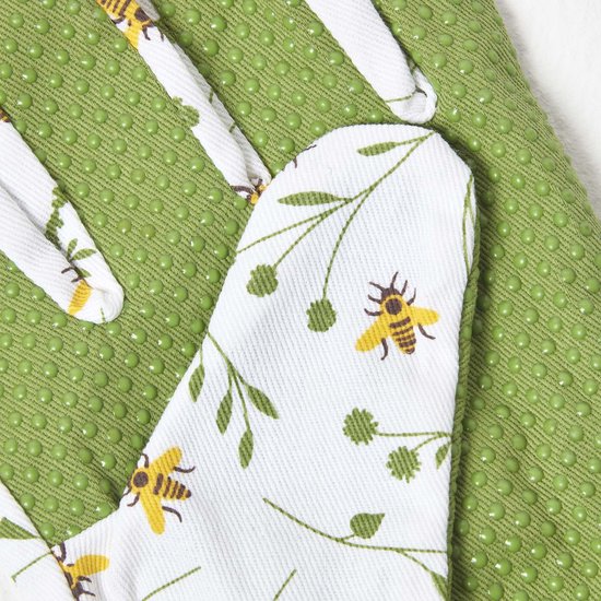 Close-up van een groene tuinhandschoen met witte antislipnoppen en een bloemen-bijenmotief.