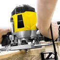 Handen bedienen gele Trotec bovenfrees bij het maken van een groef in hout.
