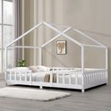 Lit maison blanc avec barreaux, décoré de coussins et de couvertures.