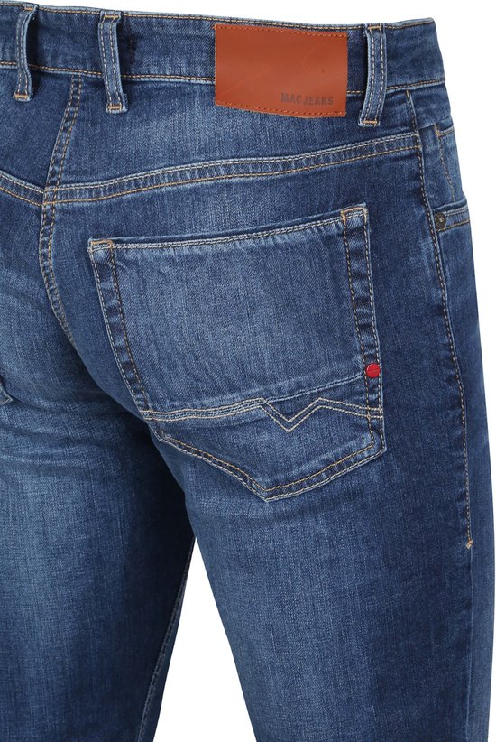 Achterkant van een blauwe jeans met een bruin lederen MAC JEANS label en geborduurde zak.