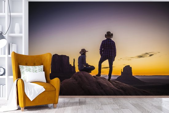 Deux cowboys dans une zone de montagne au coucher du soleil fotobehang