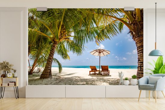 Chaises longues entre les palmiers sur une plage de Bali fotobehang