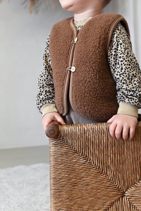 Kind met bruine teddy vest en luipaardprint shirt.