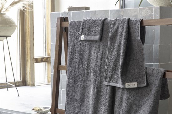Des serviettes grises Walra sont suspendues à un portant en bois dans une salle de bain.