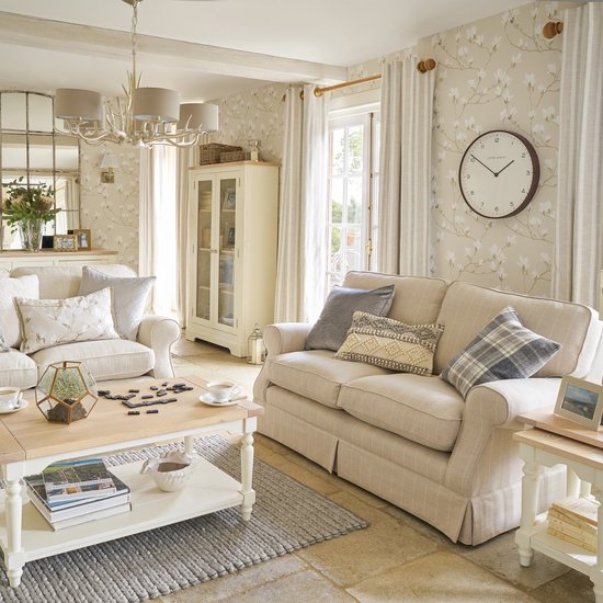 Een woonkamer met beige behang met een patroon van witte magnolia bloesems aan grijze takken.