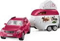 Roze auto getrokken door paardentrailer, met ruiters op de zijkant.