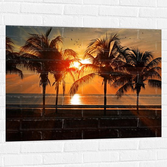 WallClassics - Muursticker - Palmbomen op het Strand bij Zonsondergang - 100x75 cm Foto op Muursticker