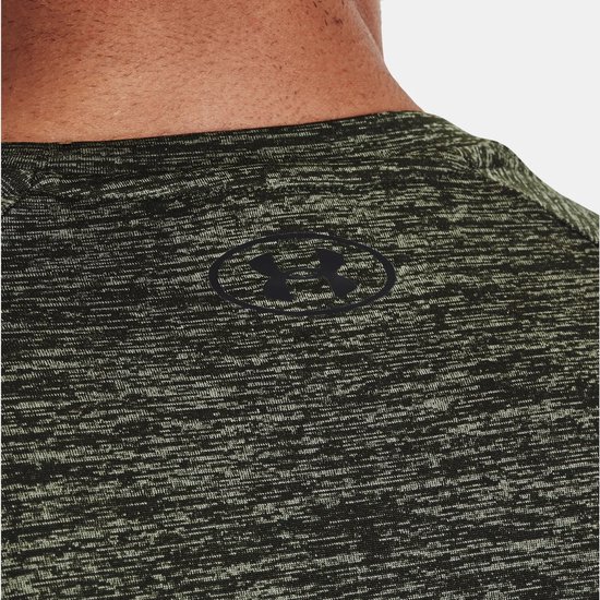 Close-up van de nek en schouder van een olijfgroen gemêleerd Under Armour sportshirt met zwart logo.