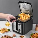 Hand tilt de mand met frietjes uit de open Aigostar frituurpan. Gefrituurde snacks en koffie ernaast.