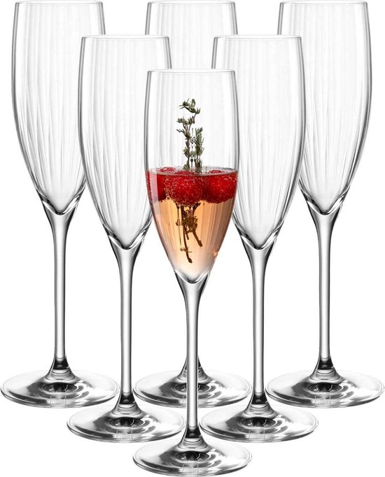 Zes glazen champagneglazen met verticale ribbels, één gevuld met roze drank, frambozen en takjes.