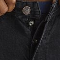 Sluiting van zwarte jeans met knopen en klinknagels.