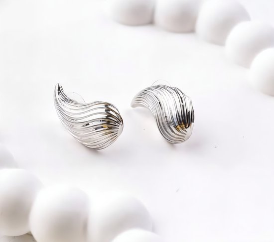 Twee zilverkleurige, gedraaide oorbellen op een witte achtergrond.