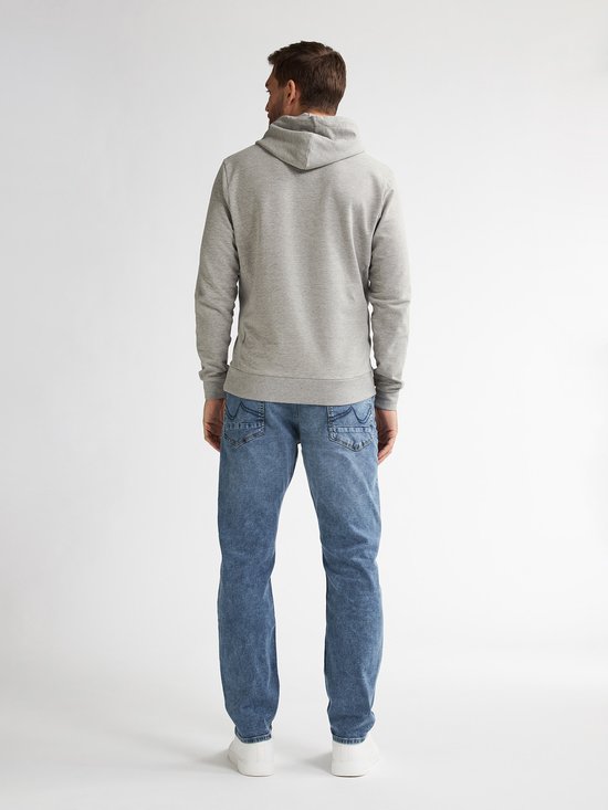Achterkant van een man in een lichtgrijze hoodie en lichtblauwe jeans met witte sneakers.