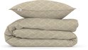 Gevouwen beige dekbedovertrek en kussen met een geometrisch patroon op witte achtergrond.