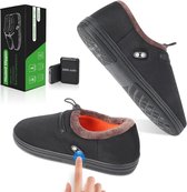 Zwarte verwarmde pantoffels, getoond met de doos, een 5000 mAh batterij en een detailopname van de zool. Een vinger drukt op de aan/uit-knop op de pantoffel.
