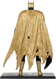 Achterkant van een actiefiguur van Batman met een gouden, gescheurde cape die over de schouders valt, zwart pak en gouden laarzen.