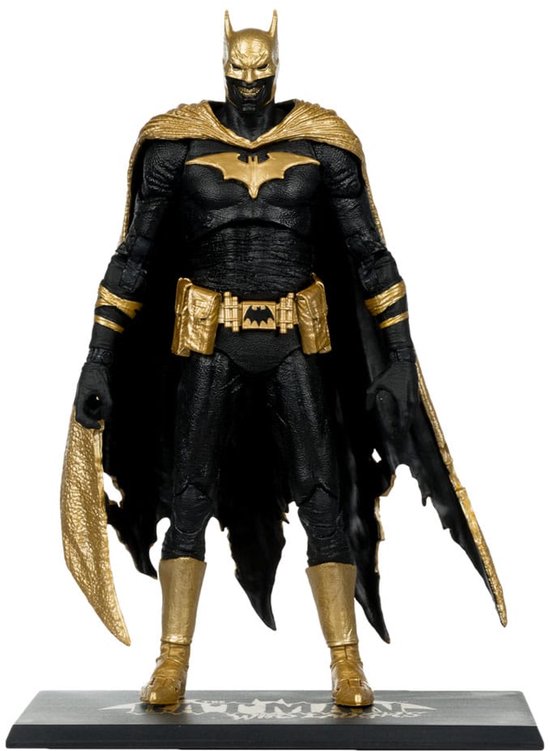Een actiefiguur van Batman in een zwart pak met gouden accenten, gouden vleermuislogo op de borst en een gescheurde gouden cape, staand op een sokkel.