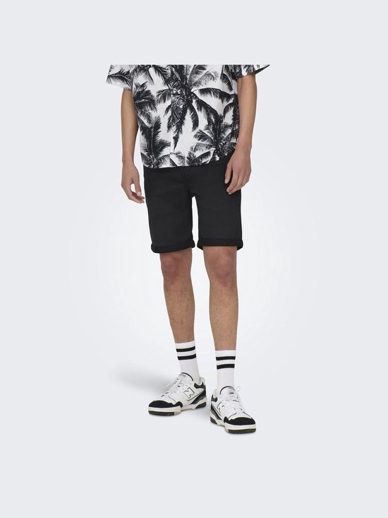 Jonge man met palmtree shirt en zwarte denim shorts, witte sokken met strepen en sneakers.