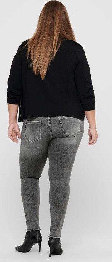 Model van achteren gezien in een zwarte jas en grijze skinny jeans met rafelige zoom.
