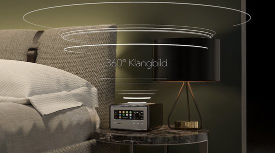 Zwarte smart radio met zilveren voorkant op een marmeren nachtkastje, omringd door grafische lijnen die 360 graden geluid suggereren.