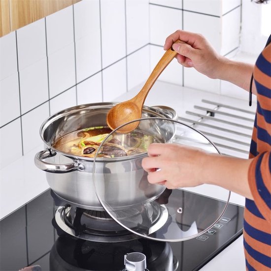 Een RVS pan met een glazen deksel wordt op een inductiekookplaat gebruikt. Een houten lepel roert in de pan.