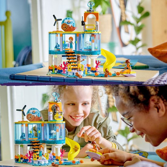 LEGO Friends Reddingscentrum met een glijbaan, 2 meisjes die spelen en de dierenset, allemaal op een houten tafel.