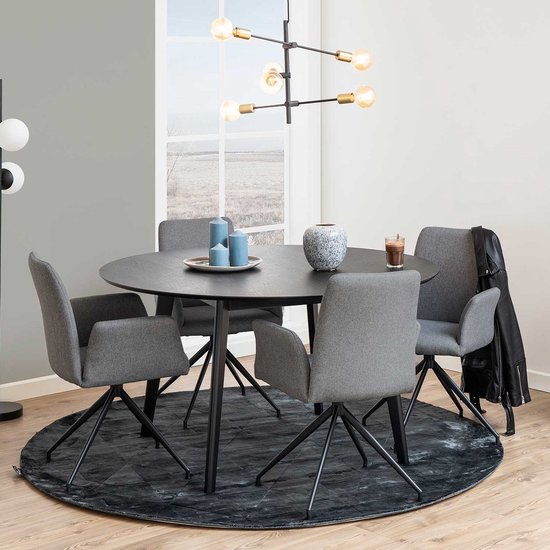 Eetkameropstelling met een ronde, zwarte tafel met vier grijze stoelen en een rond vloerkleed.