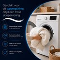 Crème deken met quiltpatroon wordt in een wasmachine gestopt, met tekst over wasbaarheid.