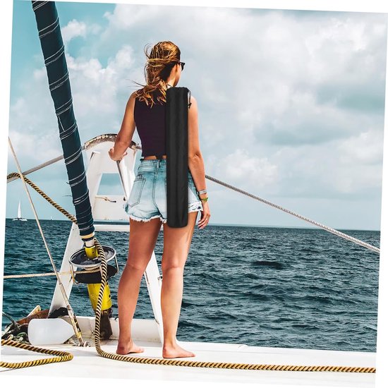 Vrouw op een zeilboot met een zwarte tas over haar schouder.