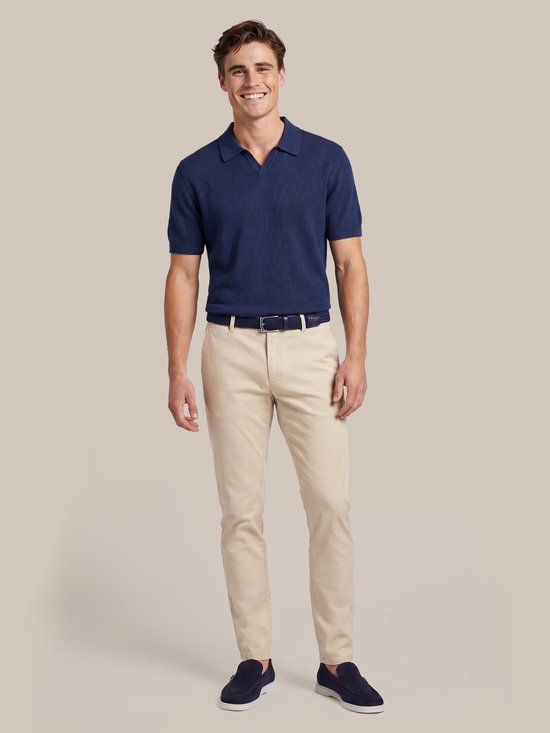 Man in een donkerblauw poloshirt en lichtbeige chino.