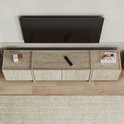 Topview van een tv-meubel van lichtbruin travertin met vier deuren, met afstandsbediening en decoratie.